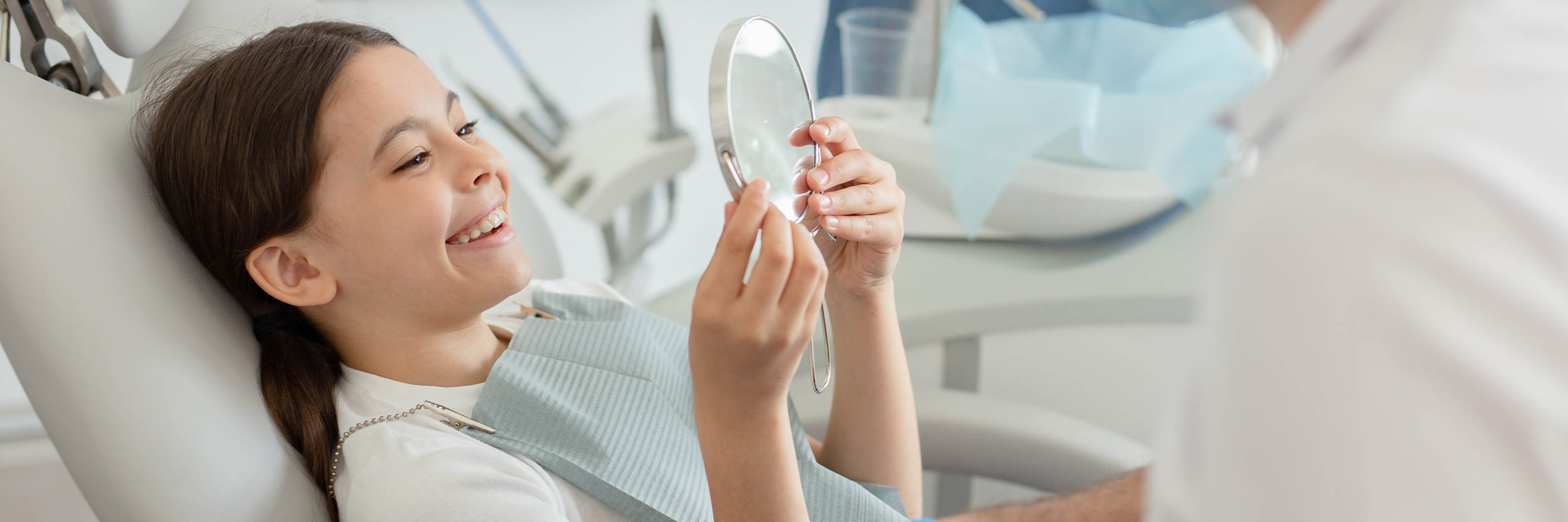 A child looking in a mirror at the dentist