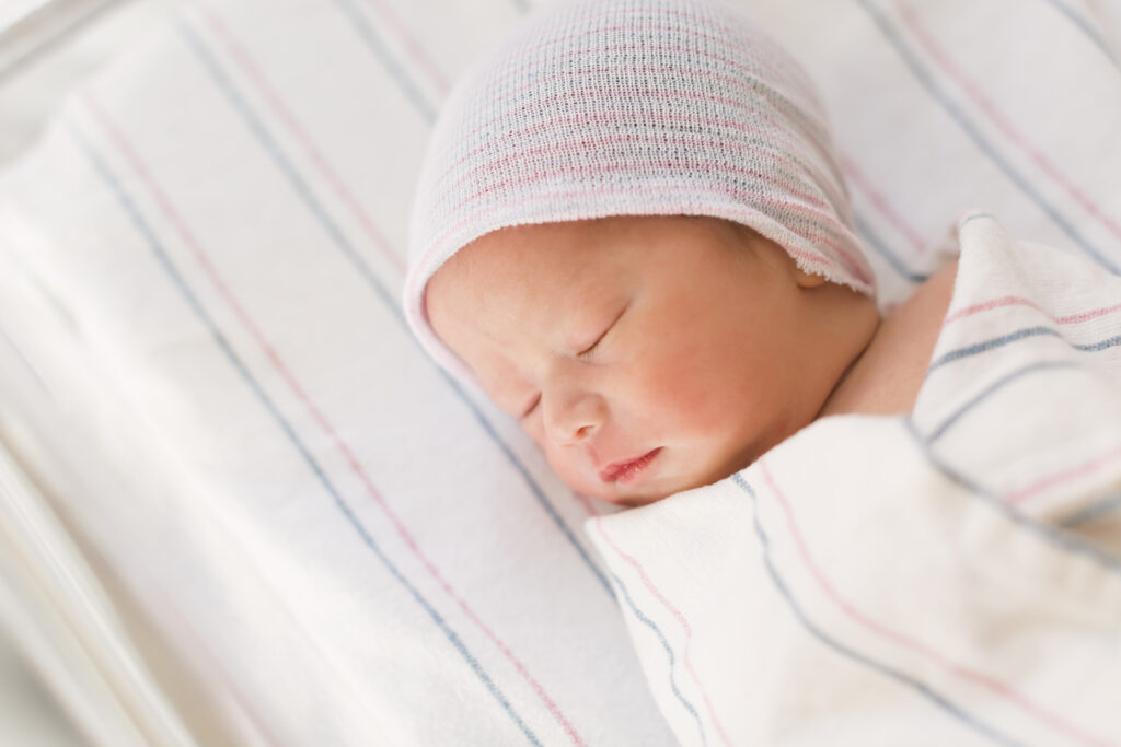 A newborn baby wrapped in a blanket with a hat on