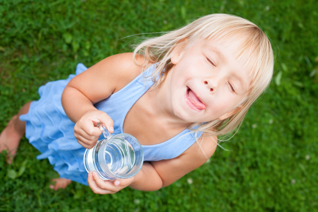 A child drinking from a glass of water outside