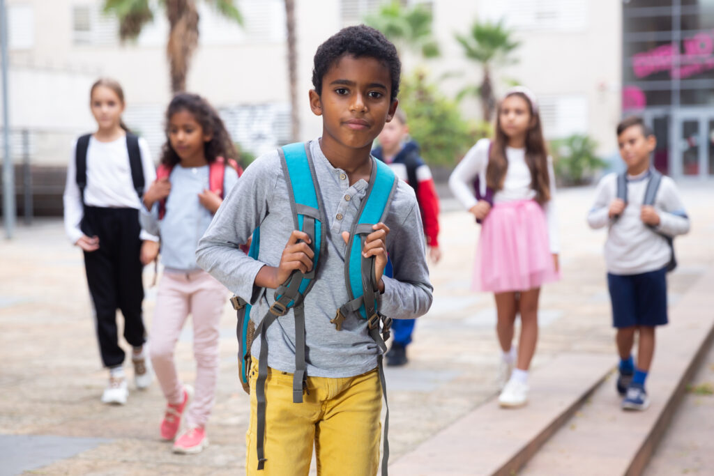 A group of young kids walking with backpacks on