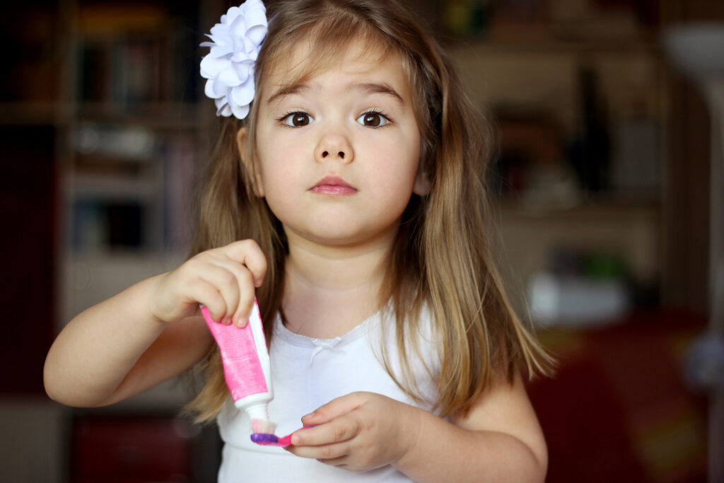 Little girl putting toothpaste on her toothbrush